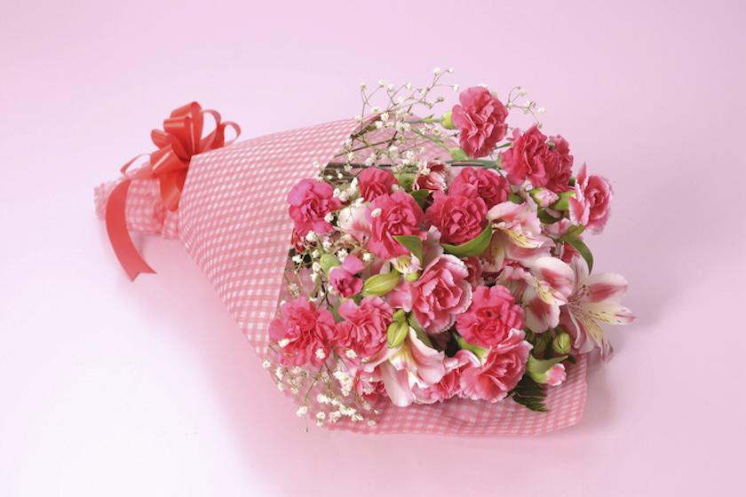 ピンク色の背景に、ピンク色のカーネーションの花束が置かれている。