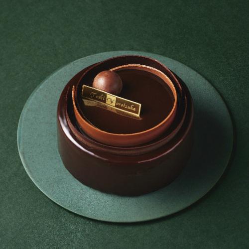 緑色の背景に、ホールのチョコレートケーキが置かれている。