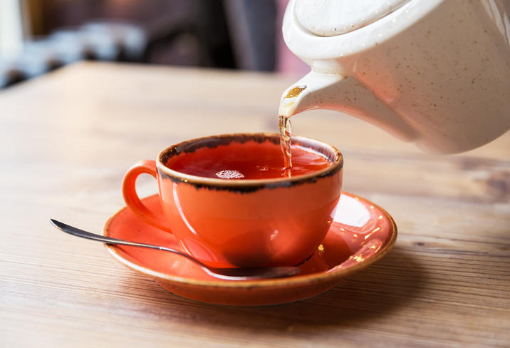 オレンジ色のティーカップに紅茶が注がれている