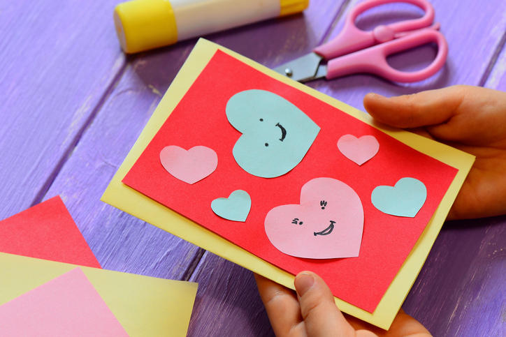 子どもが手作りのバレンタインカードを持っている。