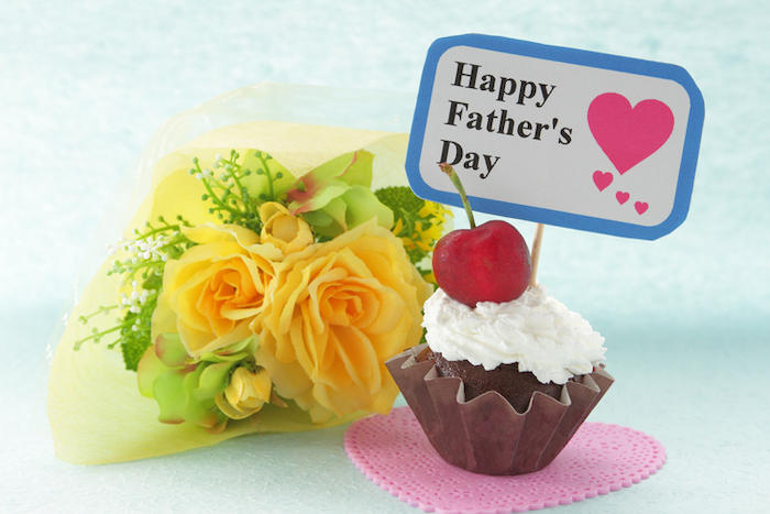 小さな黄色のバラの花束と、Happy Father's Dayのメッセージを付けたカップケーキが並んでいる