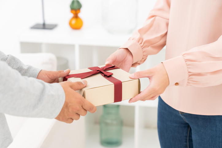 赤いリボンがかかったプレゼントを渡す女性