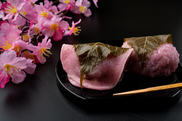 黒いお盆に関東風・関西風の桜餅が盛られ、脇に桜の花が置かれている