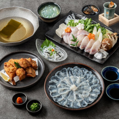 茶色っぽいテーブルに並べられたふぐの刺身、唐揚げ、てっちり（ふぐ鍋）の材料