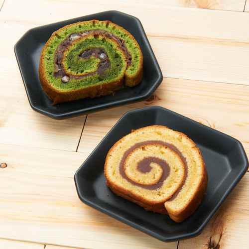 黒い皿に盛られた、自家製餡入りプレーンと抹茶のロールケーキ