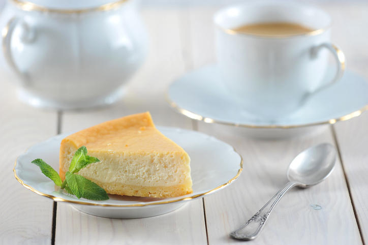 お皿にのせたチーズケーキと奥にティーカップ