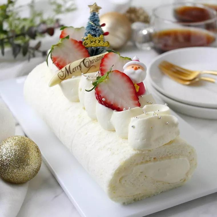 スライスしたいちごとサンタクロースの飾りがのった真っ白なロールケーキ。