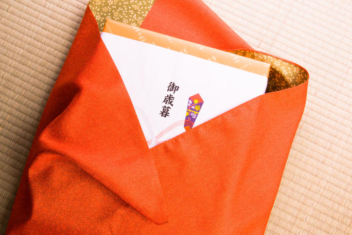 赤い風呂敷で包まれた「御歳暮」ののし付きの箱