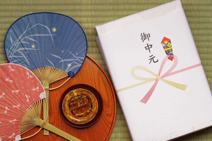 畳の上に、お中元ののし紙が付いた箱、うちわ2本、お茶が置かれている。