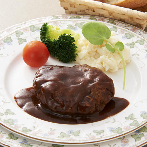 葉っぱの模様が描かれた白い皿に盛られた銀閣寺大西の煮込みハンバーグ