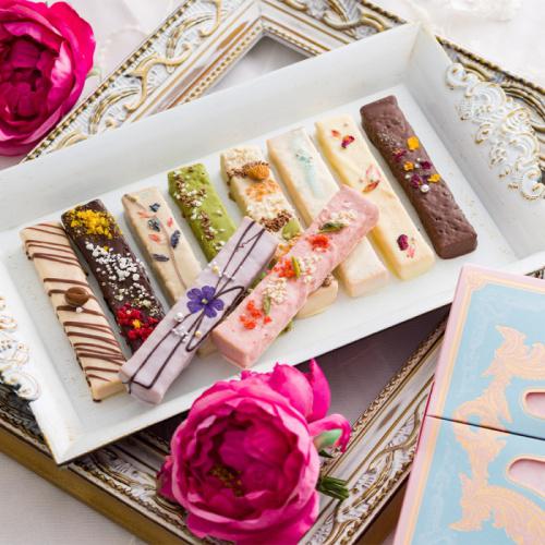白い長方形の皿の上に、チョコレートでコーティングされた10種類のバトン型ラスクが盛られている
