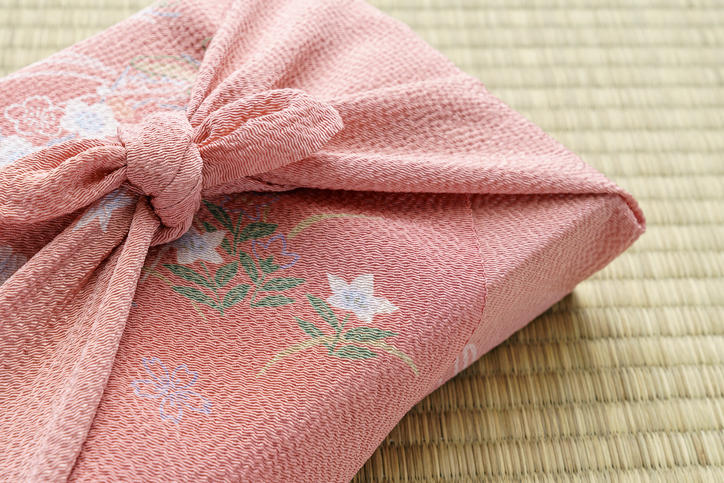 ピンクの風呂敷に包まれたギフトが畳の上に置かれている
