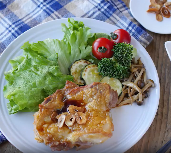 白い皿に盛られたチキンガーリックステーキと付け合わせの野菜
