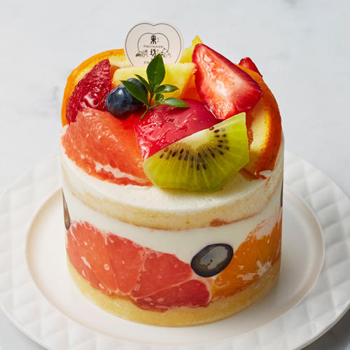 生クリームでデコレーションされたケーキにたくさんのフルーツが盛り付けられている