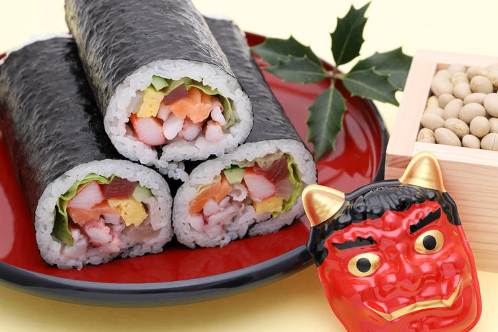 赤い盆にのせたハーフサイズの恵方巻き3本と赤鬼のお面、桝に入った豆