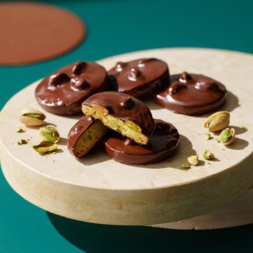 チョコでコーティングされたピスタチサブレが白い皿に並んでいる。