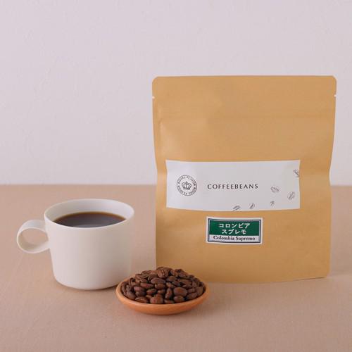 テーブルの上に、コーヒー入りカップ、コーヒー豆、茶色の袋が置かれている。