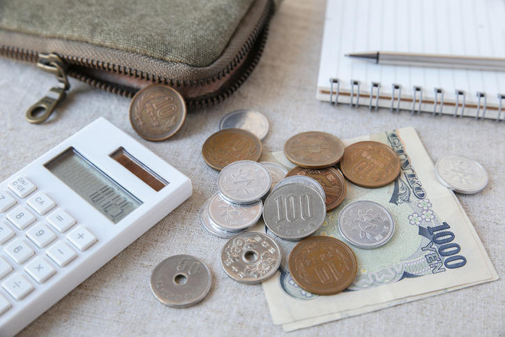 布の上に広げられた日本の通貨と電卓と財布とノート