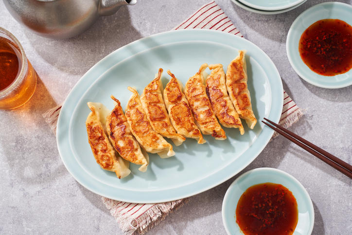 水色の皿に、焼き餃子が8個盛られている様子
