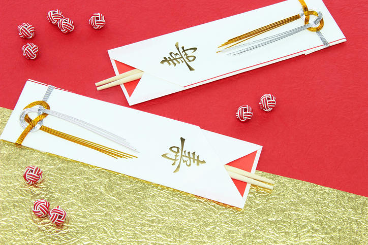 赤と金の和紙の上に置かれた2膳の祝い箸