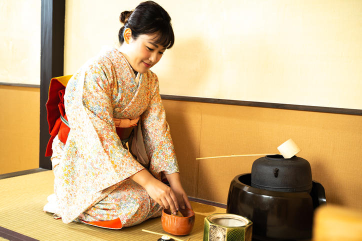 着物を着た女性が抹茶をたてている。