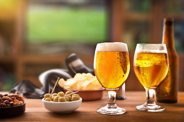 テーブルに置かれたビール入りのグラスとおつまみ