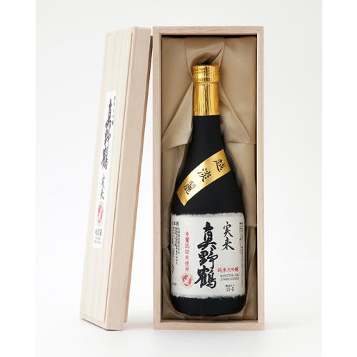 ベージュの布が敷かれた桐箱に、「真野鶴」と書かれたラベルが貼られた黒い日本酒ボトルが収められている