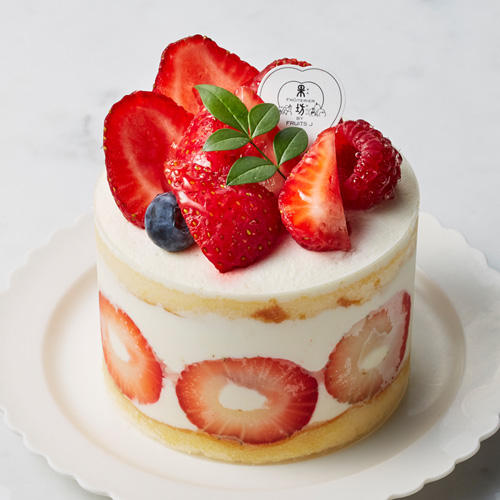 生クリームがデコレーションされたケーキにベリーが盛り付けられている
