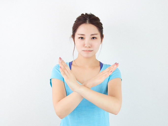 両手でバツ印を作る青いTシャツの女性