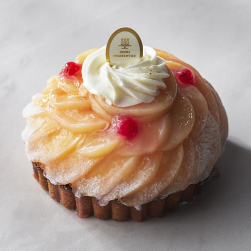 ホイップクリームと白桃でデコレーションされたホールのタルトケーキ