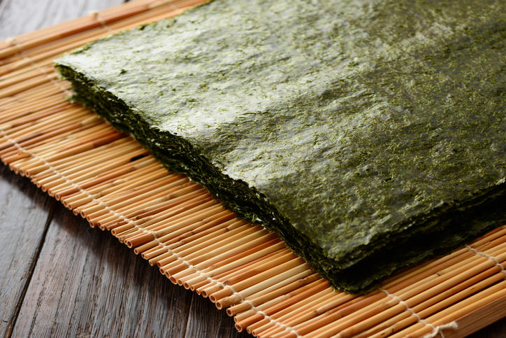 ダークウッドのテーブルに置かれた巻き簀の上にある重ねられた焼きのり