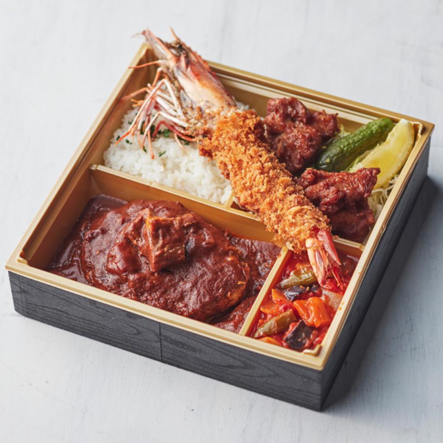 黒と金のお弁当箱に入ったハンバーグとエビフライの弁当