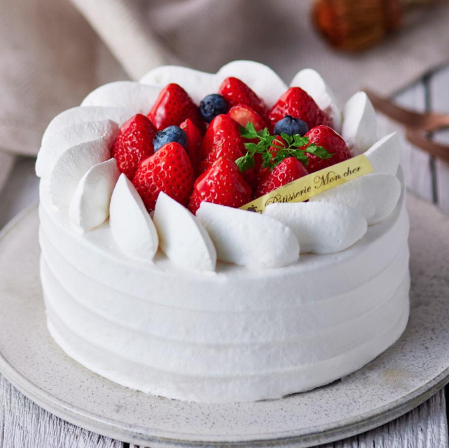 グレーの丸皿に乗ったいちごがトッピングされたホールのショートケーキ