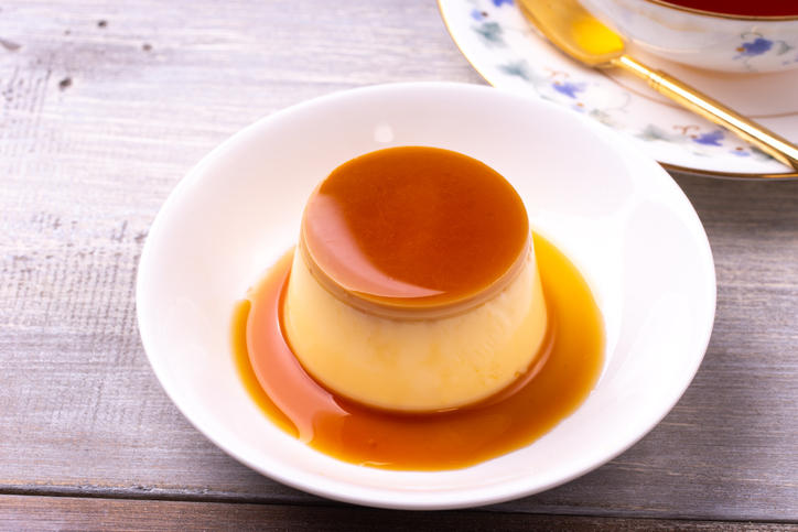 木製のテーブルにのっている皿に盛り付けられたプリン