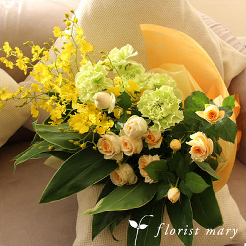 白い布張りソファーの上の黄色いバラ、黄緑のカーネーション、オンシジウムの花束