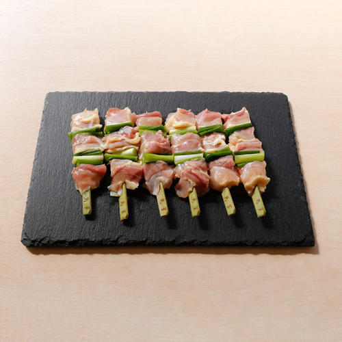 黒色のスレートプレートに生の焼き鳥串が6本並んでいる。