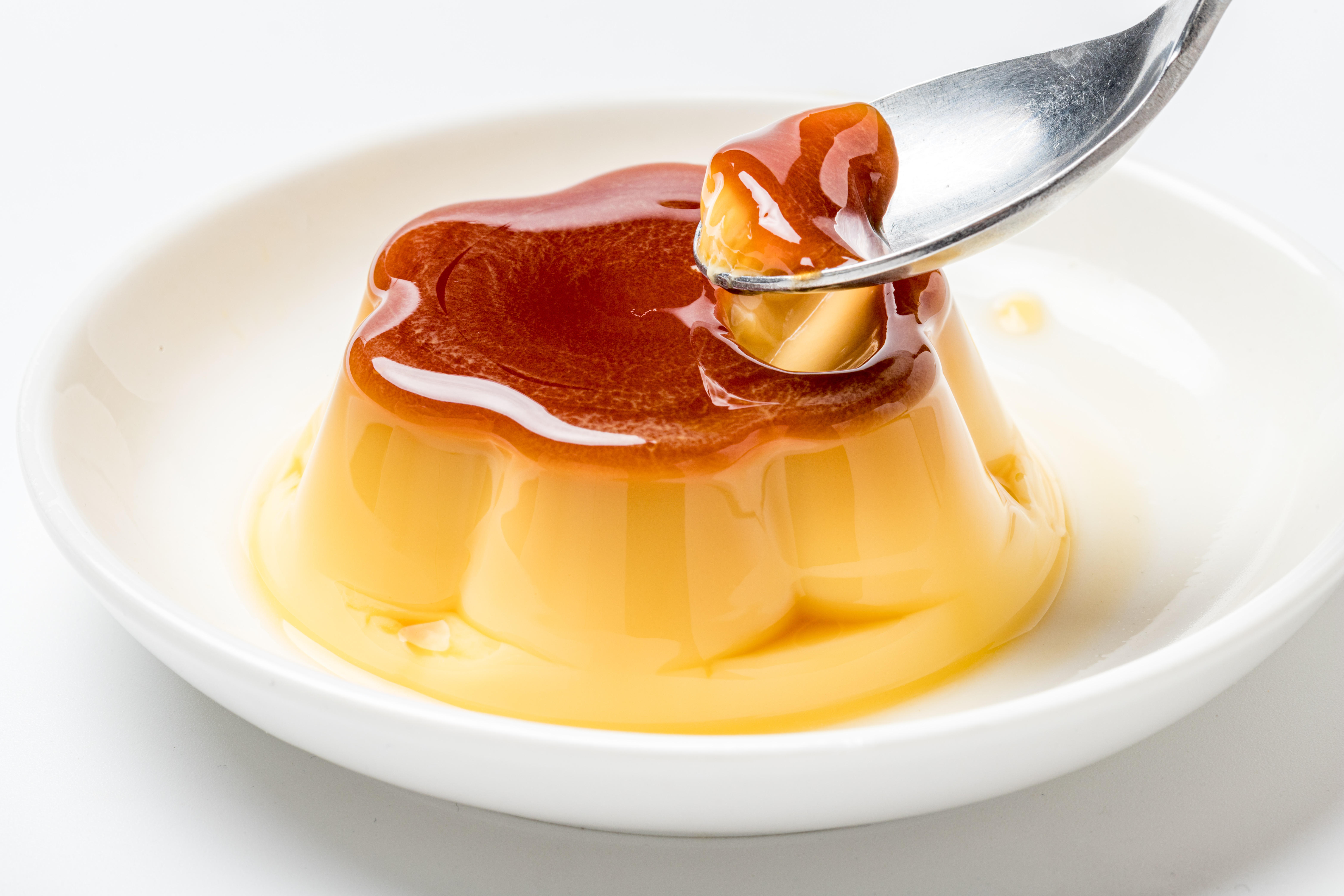 白い皿にのったプリンをスプーンですくっている。