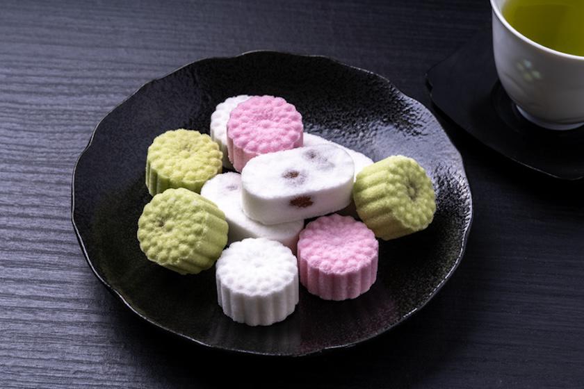 黒色の皿に、緑・白・ピンクの干菓子が盛られている。