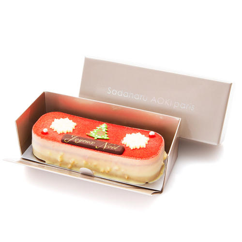 雪の結晶とクリスマスツリーの飾りがのった横長の赤色のケーキ。