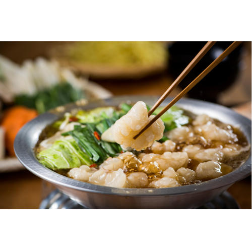 箸で摘んだもつと煮立っているもつ鍋