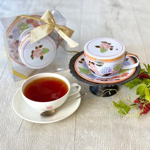 デンメアティーハウスのティーカップ型の紅茶缶と紅茶が注がれた白いティーカップが置かれている
