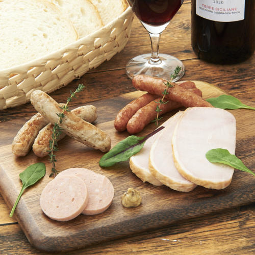 木のプレートに盛り付けられたハムやソーセージと、横に並ぶワインとパン