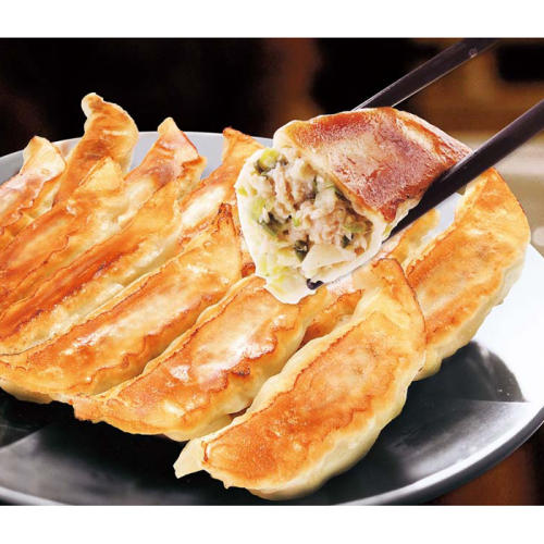皿に盛られた宇都宮餃子館の餃子と半分に切られた餃子を箸で持ち上げる様子