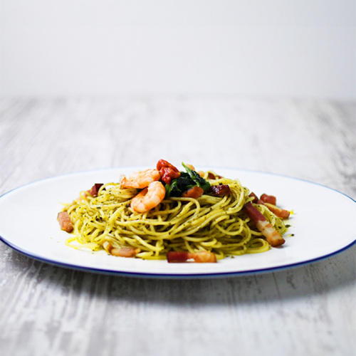 皿の上にベーコンとエビが入ったジェノベーゼパスタが盛り付けられている