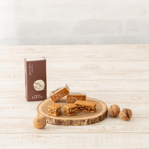 木のトレーの上にクルミッ子が置かれており、そのまわりにクルミと菓子箱が並んでいる
