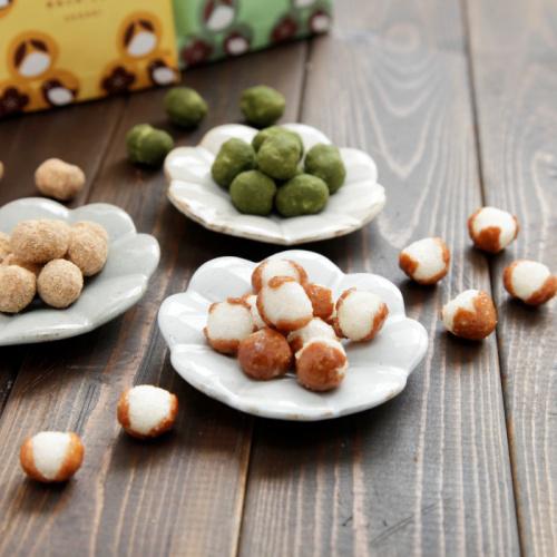 木製の背景に置かれた白い花形の3枚の小皿の上のもち米菓子