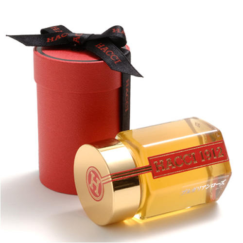 黒いリボンがかかった赤い円筒のギフトボックスと、金の蓋がついたはちみつ入りの瓶