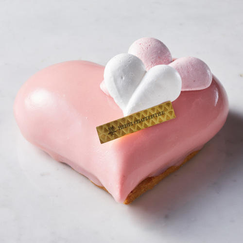 灰色の背景に置かれたピンク色のハートのケーキ