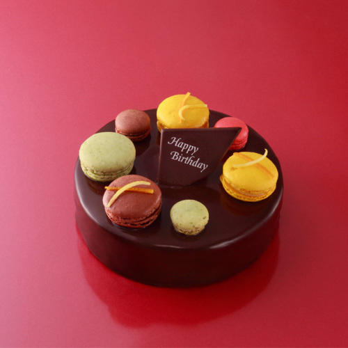 色とりどりのマカロンがのったホールのチョコレートケーキ