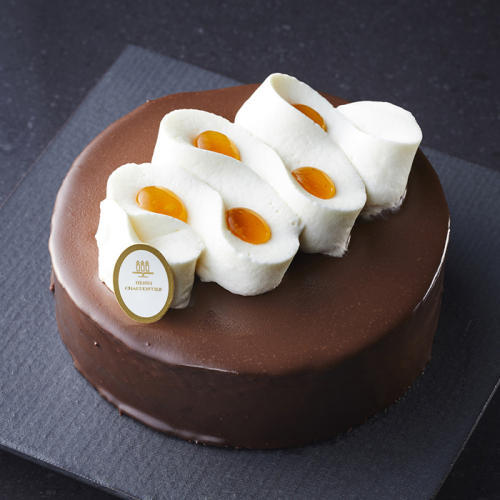 生クリームとアプリコットジャムでデコレーションされたホールのチョコレートケーキ